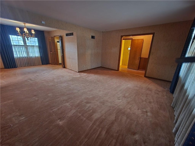 spare room with carpet flooring and a notable chandelier