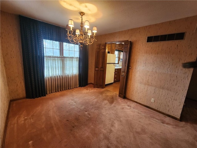 empty room with carpet and a notable chandelier