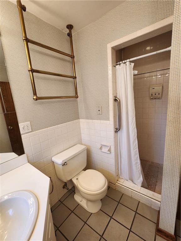 bathroom featuring tile walls, vanity, toilet, tile patterned floors, and a shower with shower curtain