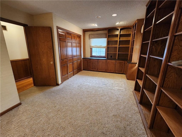 unfurnished office with wooden walls, light colored carpet, and a textured ceiling