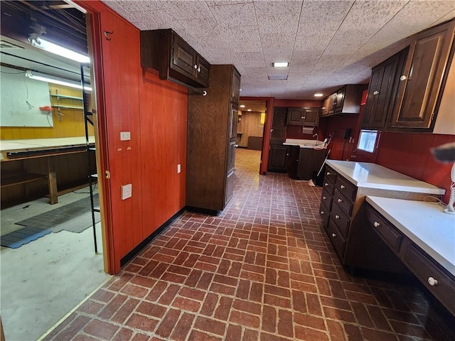 kitchen featuring dark brown cabinets and wood walls