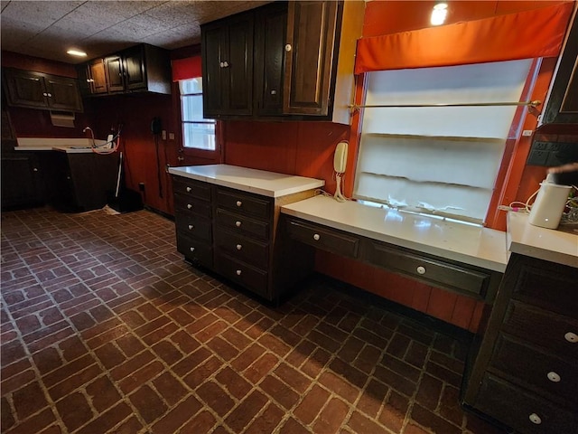 kitchen featuring built in desk, sink, and dark brown cabinets