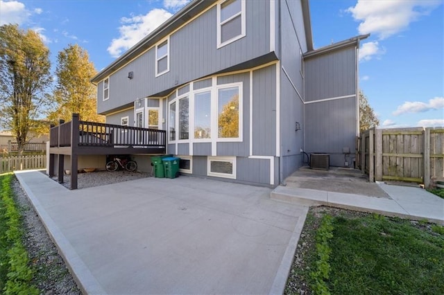 rear view of property with central AC unit, a deck, and a patio area