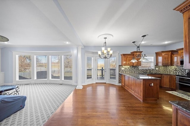 kitchen with decorative light fixtures, decorative backsplash, dark hardwood / wood-style floors, a notable chandelier, and stove