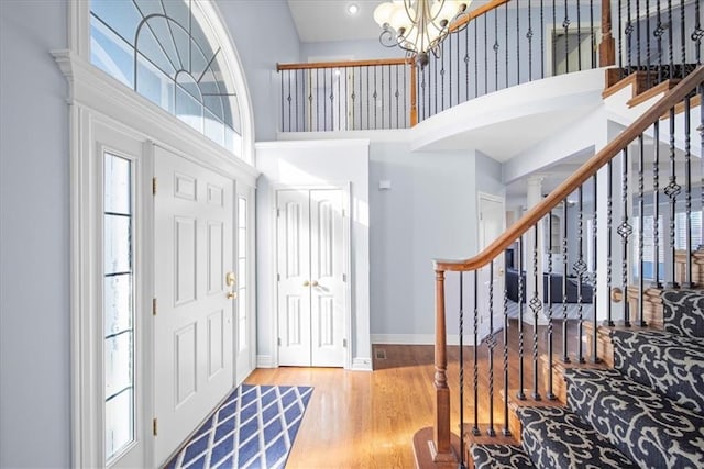 foyer with hardwood / wood-style flooring, a high ceiling, and an inviting chandelier