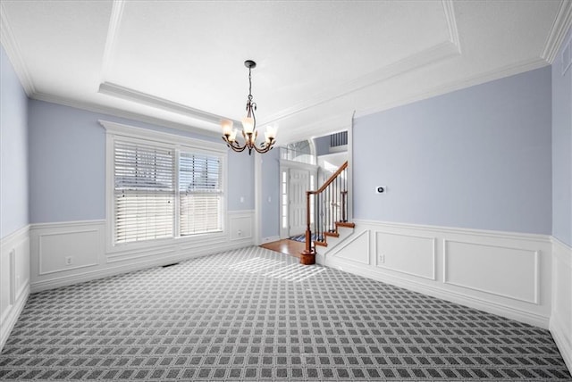 unfurnished dining area with a raised ceiling, crown molding, a chandelier, and carpet flooring