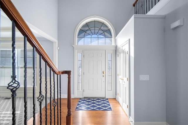 entrance foyer with a towering ceiling and light hardwood / wood-style flooring