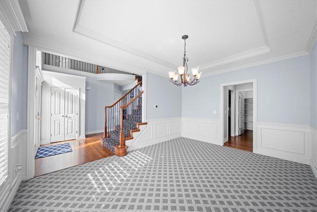 foyer with an inviting chandelier, crown molding, dark carpet, and a tray ceiling