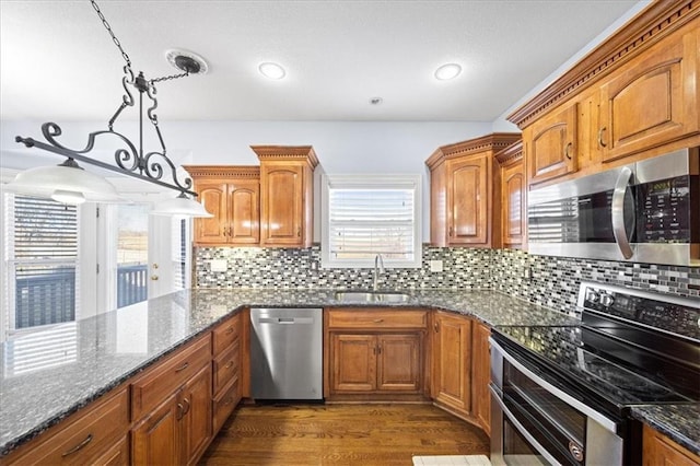 kitchen featuring backsplash, dark stone countertops, sink, hanging light fixtures, and stainless steel appliances