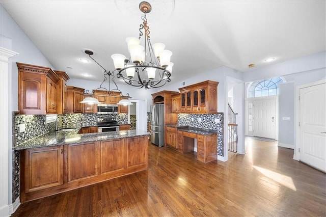 kitchen with decorative light fixtures, kitchen peninsula, sink, an inviting chandelier, and stainless steel appliances