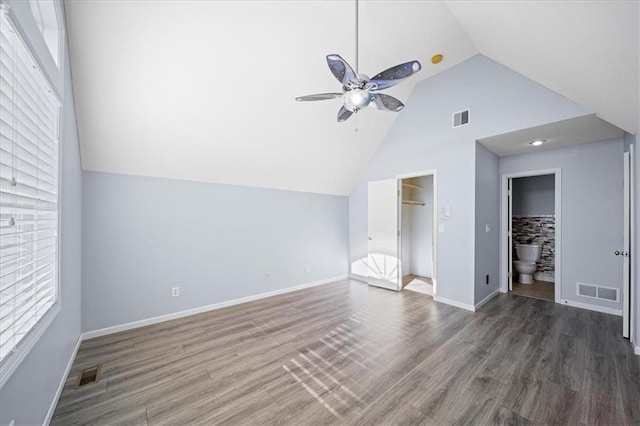 unfurnished bedroom featuring ensuite bathroom, ceiling fan, dark hardwood / wood-style floors, lofted ceiling, and a walk in closet