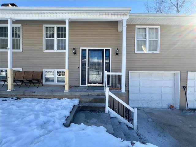 snow covered property entrance with a garage