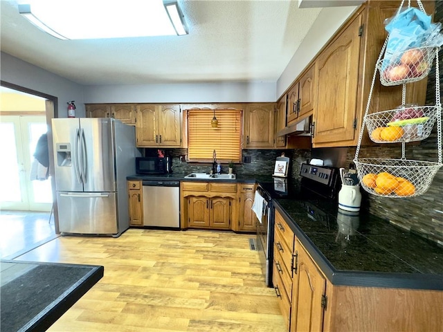 kitchen featuring sink, backsplash, black appliances, and light wood-type flooring