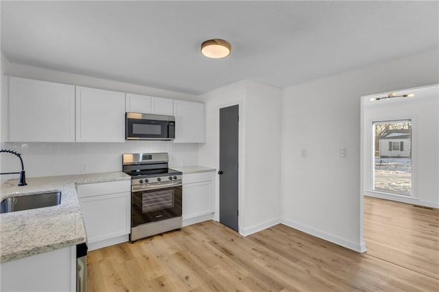 kitchen with white cabinets, light stone countertops, sink, and stainless steel appliances