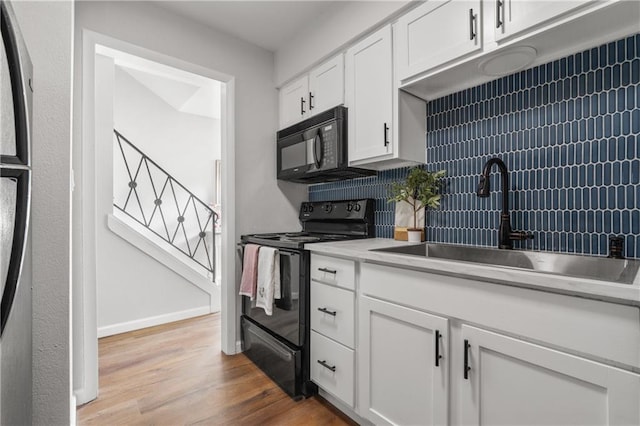 kitchen with black appliances, white cabinetry, decorative backsplash, sink, and light hardwood / wood-style flooring