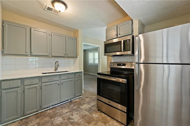 kitchen featuring decorative backsplash, appliances with stainless steel finishes, sink, and gray cabinetry