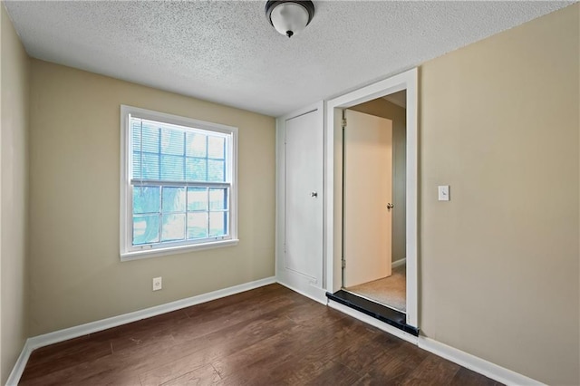 unfurnished bedroom with dark hardwood / wood-style flooring and a textured ceiling