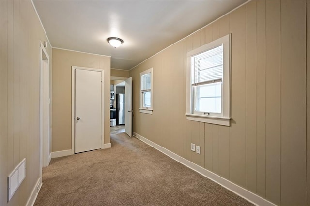 corridor featuring light carpet and wood walls