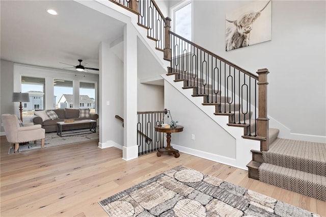 staircase featuring ceiling fan and hardwood / wood-style floors