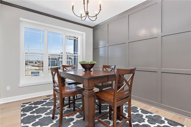 dining space with an inviting chandelier, crown molding, and light hardwood / wood-style flooring