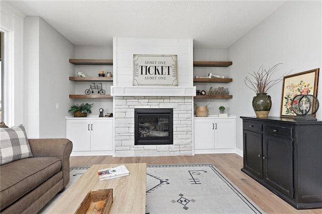 living room with a stone fireplace and light wood-type flooring