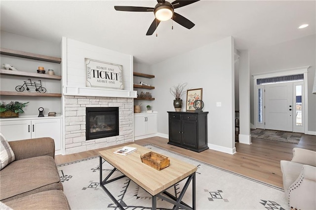 living room featuring ceiling fan, a fireplace, and light hardwood / wood-style floors