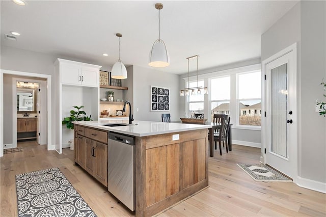 kitchen featuring sink, light hardwood / wood-style flooring, a kitchen island with sink, white cabinets, and stainless steel dishwasher