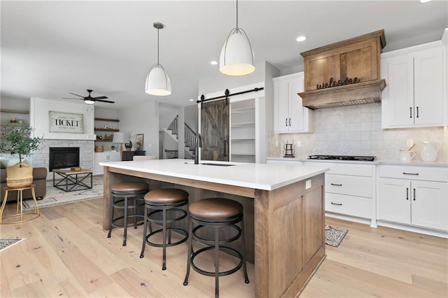 kitchen with white cabinetry, a barn door, pendant lighting, and a center island with sink