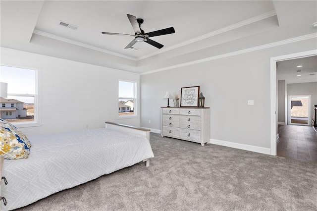 bedroom with ornamental molding, carpet flooring, a raised ceiling, and multiple windows