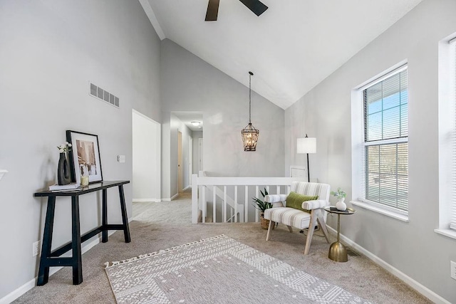 living area featuring high vaulted ceiling, light colored carpet, and ceiling fan with notable chandelier