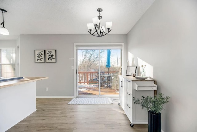 doorway featuring light hardwood / wood-style floors, a textured ceiling, and a chandelier