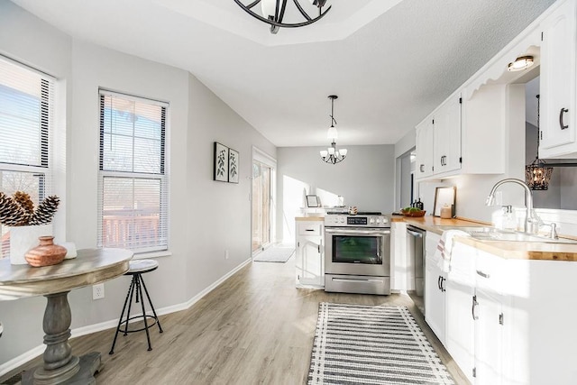 kitchen with white cabinets, appliances with stainless steel finishes, sink, and pendant lighting