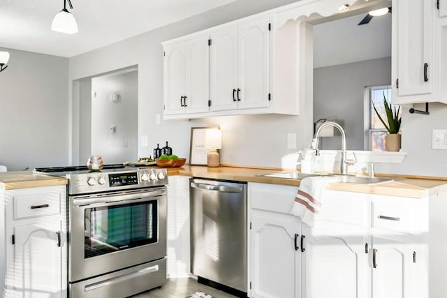 kitchen with pendant lighting, white cabinets, appliances with stainless steel finishes, sink, and kitchen peninsula