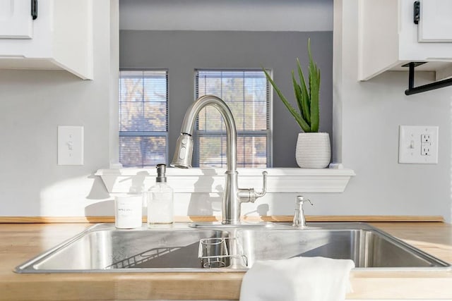 interior details featuring white cabinetry and sink