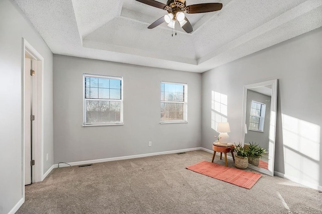 spare room with carpet floors, a textured ceiling, a raised ceiling, and ceiling fan