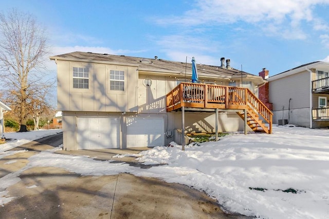 snow covered house with a garage and a deck