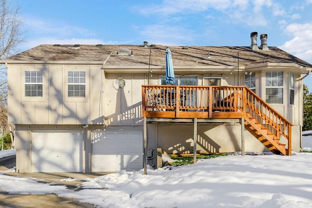 snow covered property with a deck and a garage