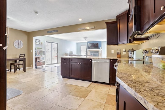 kitchen with sink, a textured ceiling, light tile patterned floors, appliances with stainless steel finishes, and light stone countertops