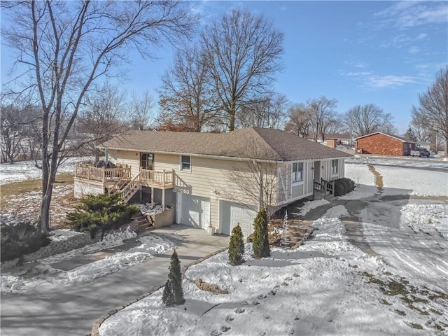 snow covered property with a garage and a deck