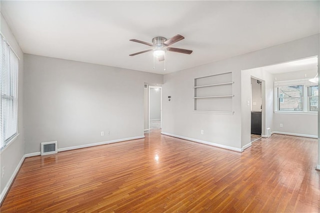 spare room with ceiling fan, wood-type flooring, and a wealth of natural light