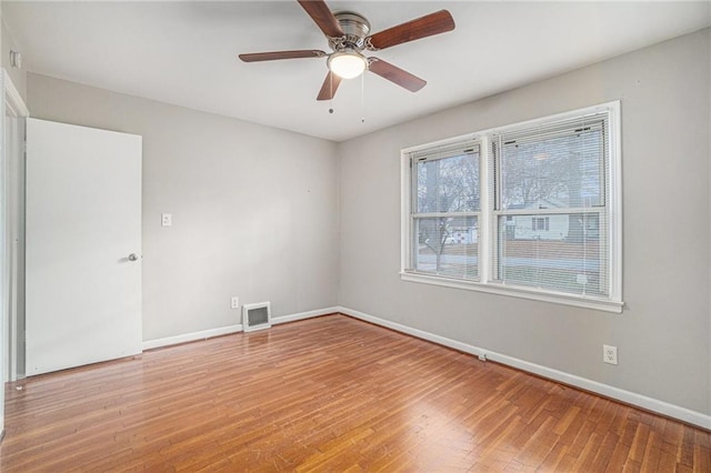 empty room featuring ceiling fan, wood-type flooring, and plenty of natural light