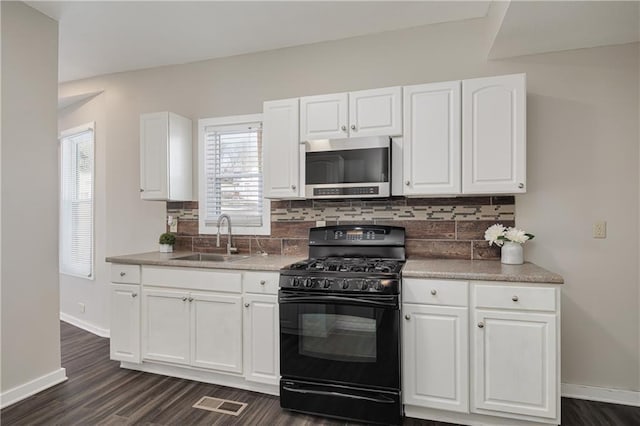 kitchen with gas stove, decorative backsplash, sink, dark wood-type flooring, and white cabinets