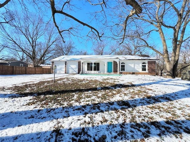 snow covered rear of property featuring a garage