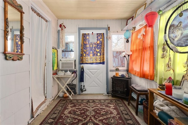 mudroom with a wood stove, cooling unit, and concrete flooring