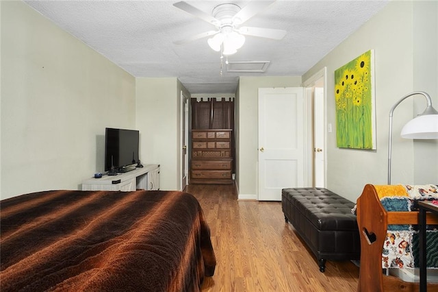 bedroom with light wood-type flooring, ceiling fan, and a textured ceiling