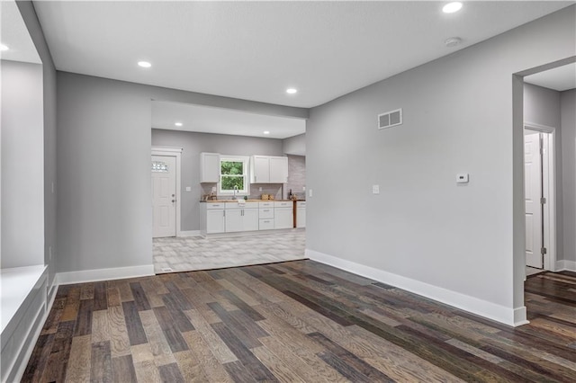 unfurnished living room with sink and dark hardwood / wood-style floors