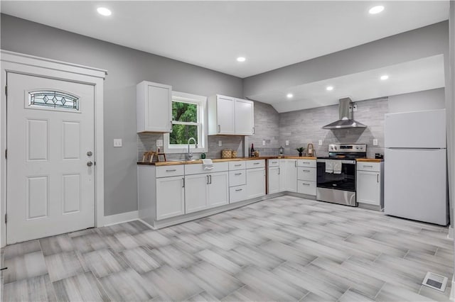 kitchen with white cabinetry, white refrigerator, wall chimney exhaust hood, and stainless steel range with electric cooktop