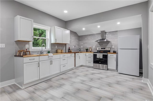 kitchen featuring wood counters, white cabinetry, wall chimney range hood, white fridge, and stainless steel range with electric stovetop