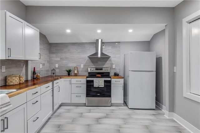 kitchen featuring stainless steel range with electric stovetop, white cabinets, wall chimney range hood, white refrigerator, and butcher block countertops