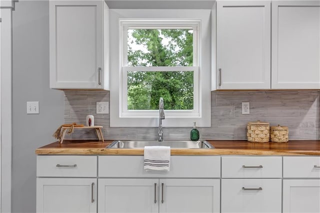 kitchen featuring decorative backsplash, sink, white cabinets, and wooden counters